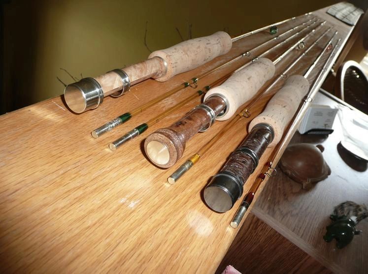 Collection of bamboo fly rods with cork handles on a wooden surface